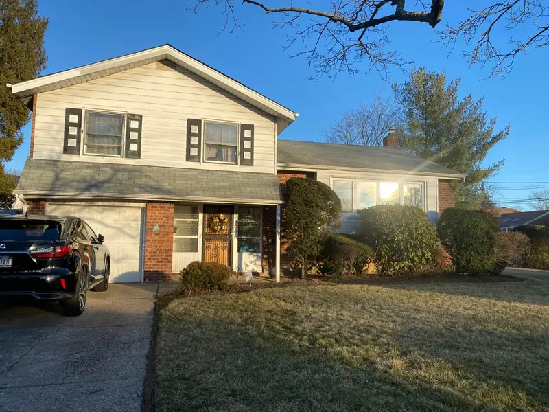 Split-level with a brick-faced garage and a front lawn, Baldwin, NY